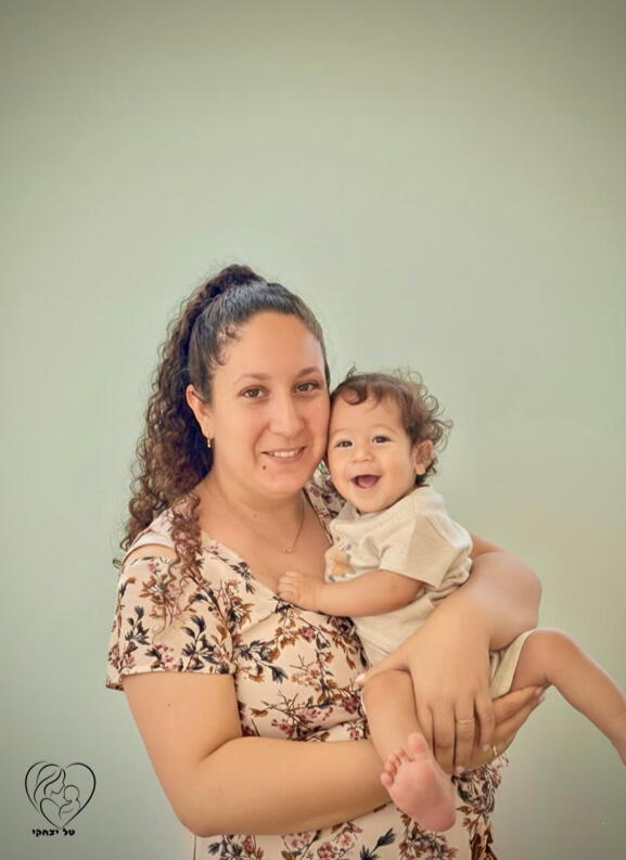 טל יצחקי מדריכת ליווי התפתחותי במעלה אדומים וירושלים, בתמונה טל מחזיקה תינוק שניהם מחייכים.